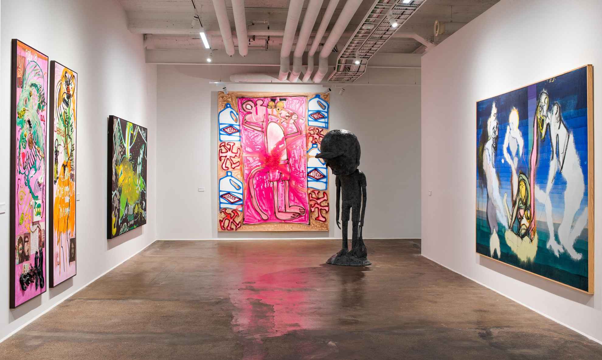 An exhibition with a large statue in a room and paintings on the wall.