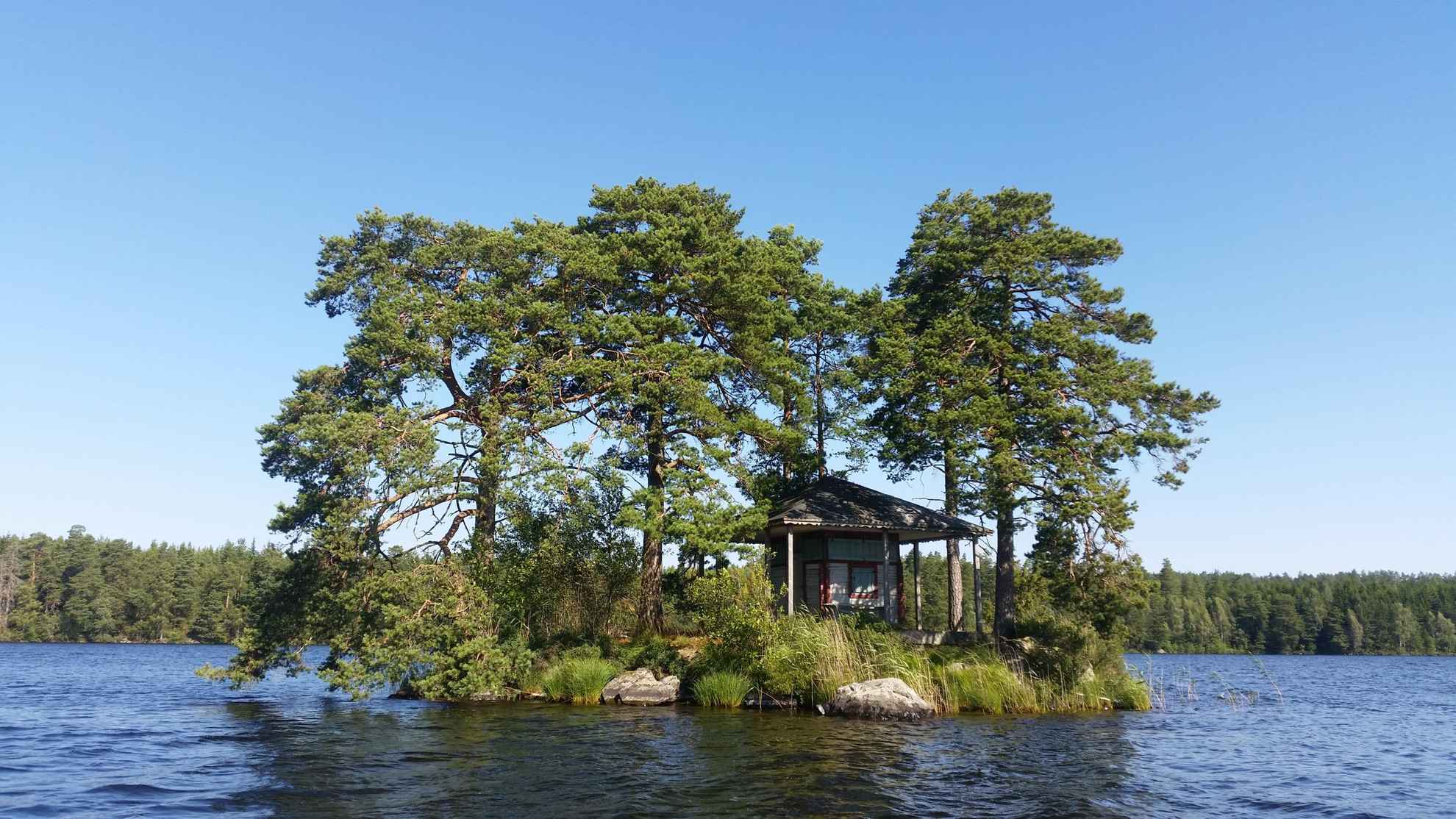 A very small island with a house and a few trees.