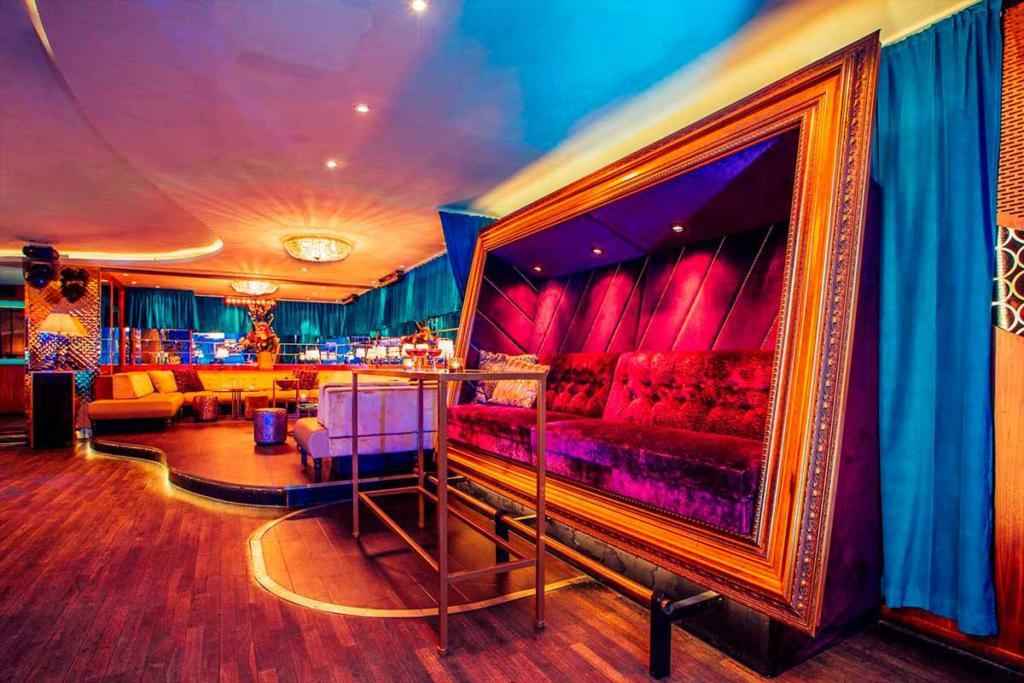 A nightclub with velvet furniture, wooden floors and blue curtains.