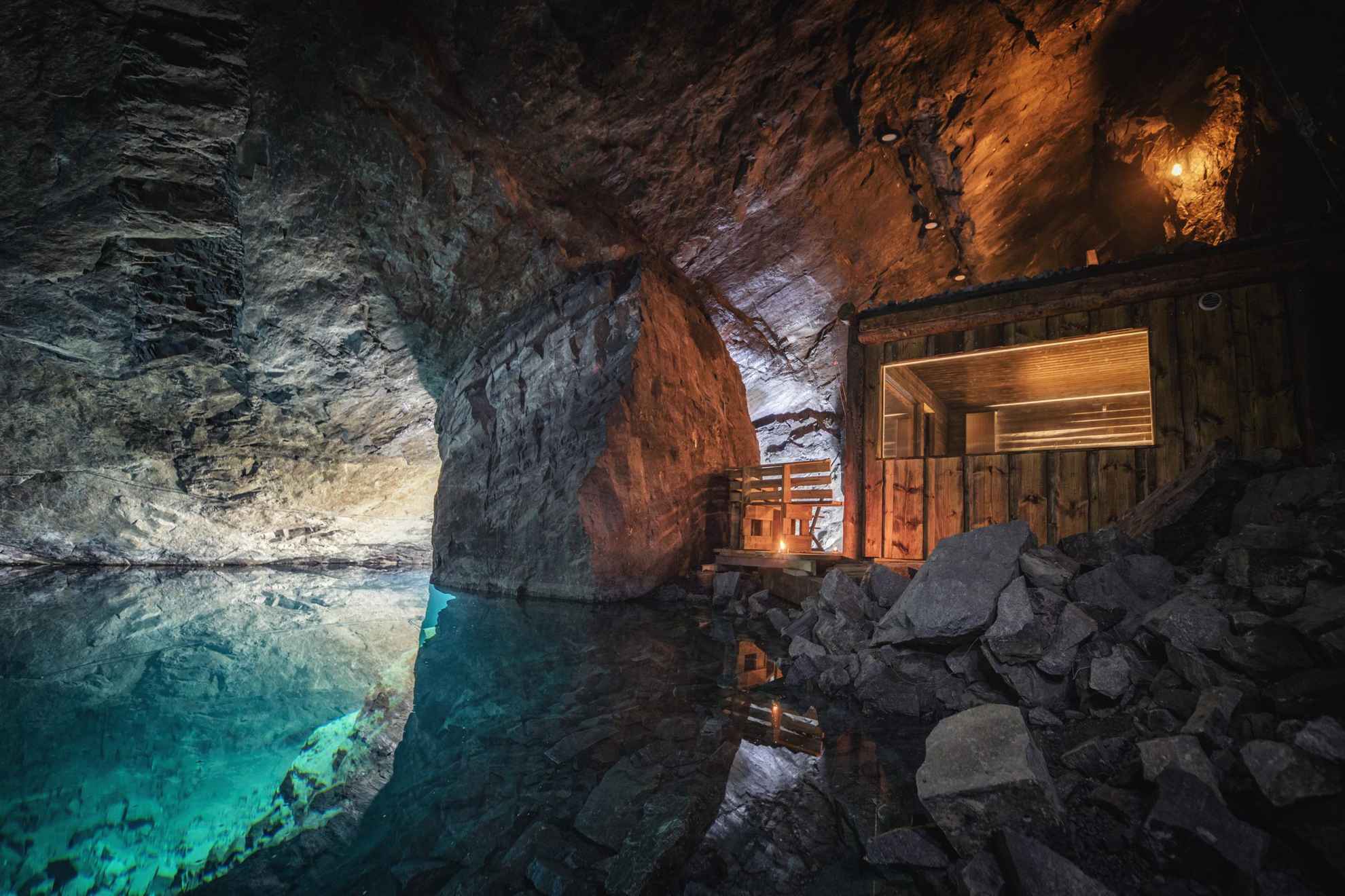 A wooden sauna by the blue clear water inside a mine.
