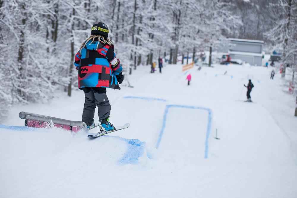 A child skiing down a ski slope with small jumps.