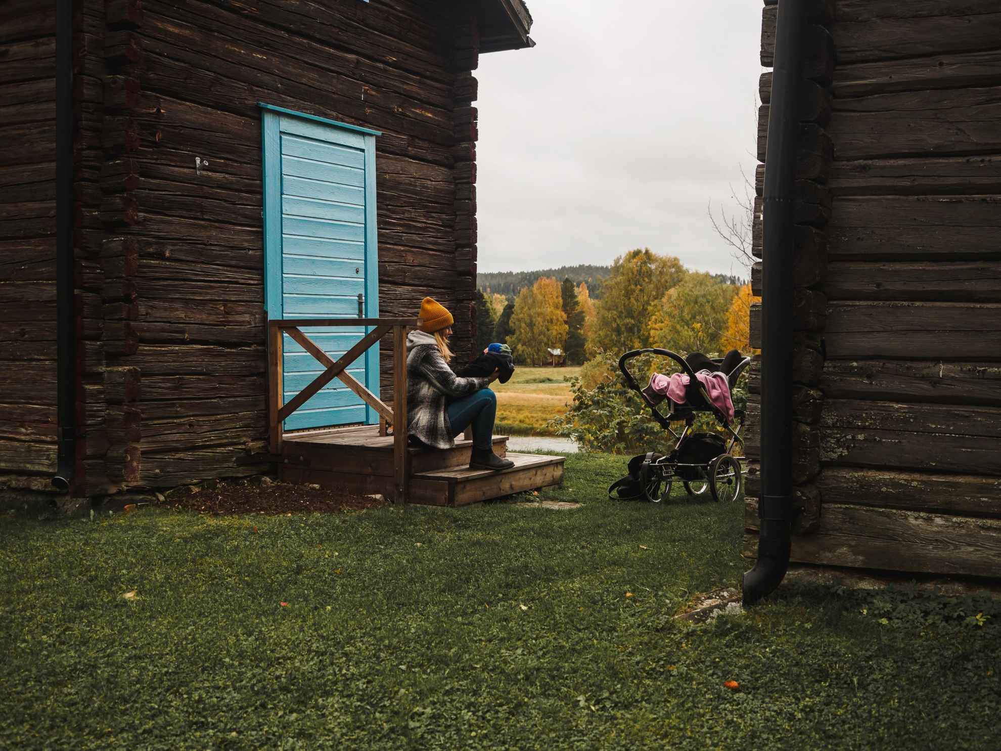 A woman sitting on a wooden porch with a baby. The stroller stands next to them.