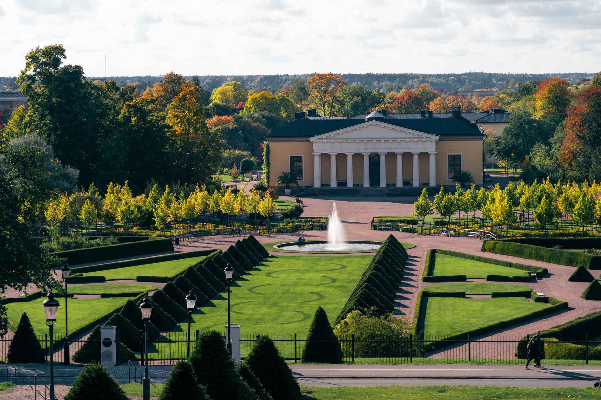 Botanical Garden in Uppsala. Autumn with coloured leafs mixed with green. View over the baroque garden. The building Linneanum in the background.
