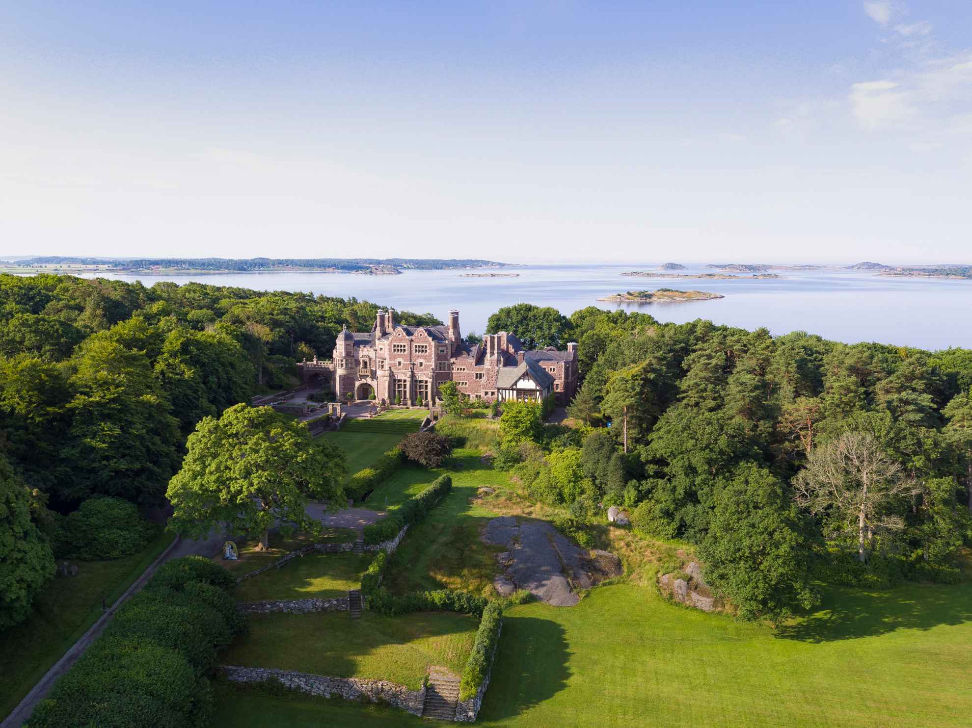 An aerial view of Tjolöholm Castle next to the water and surrounded by greenery during summer.