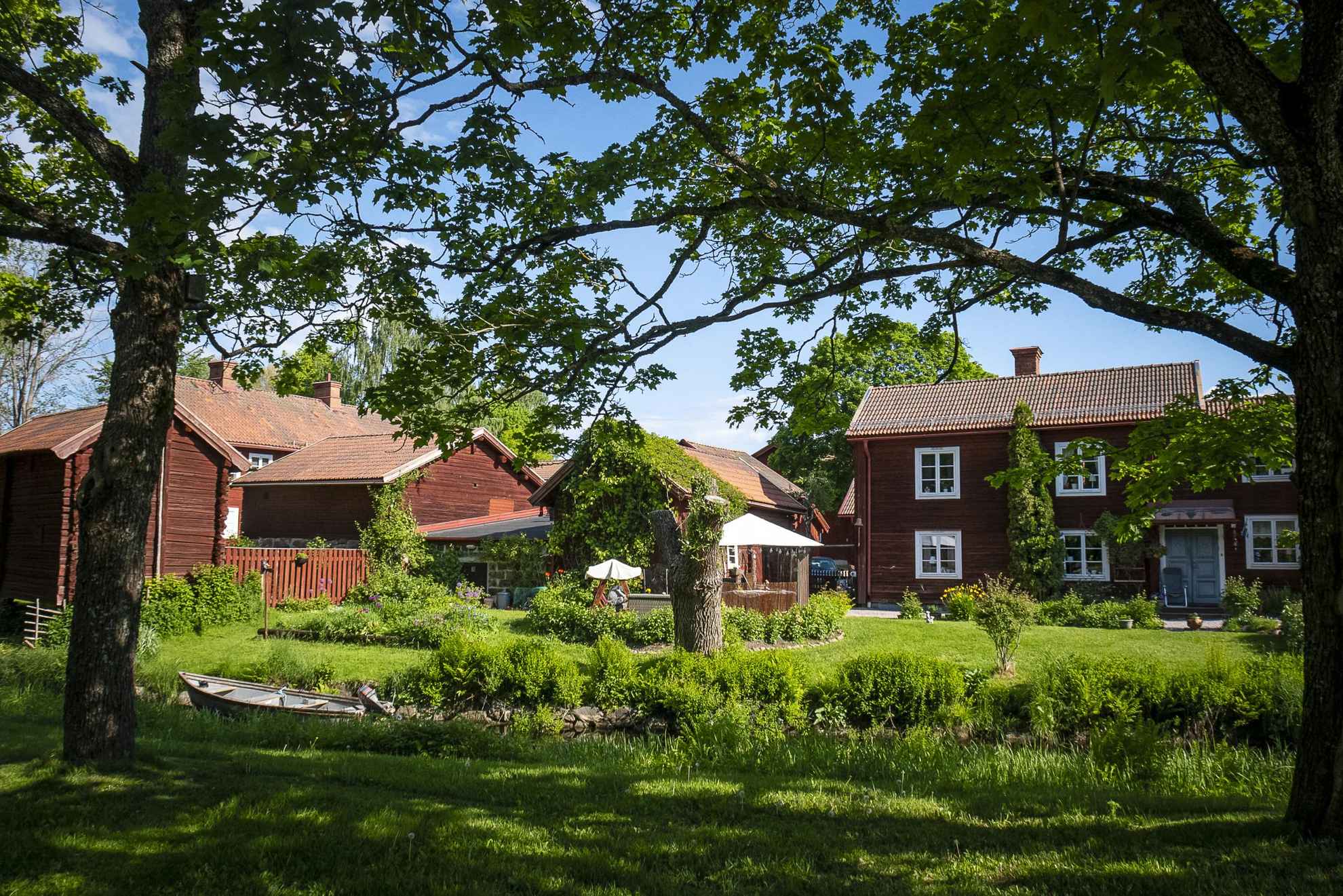 Several traditional houses painted with the famous paint Falu Rödfärg surrounded by greenery.