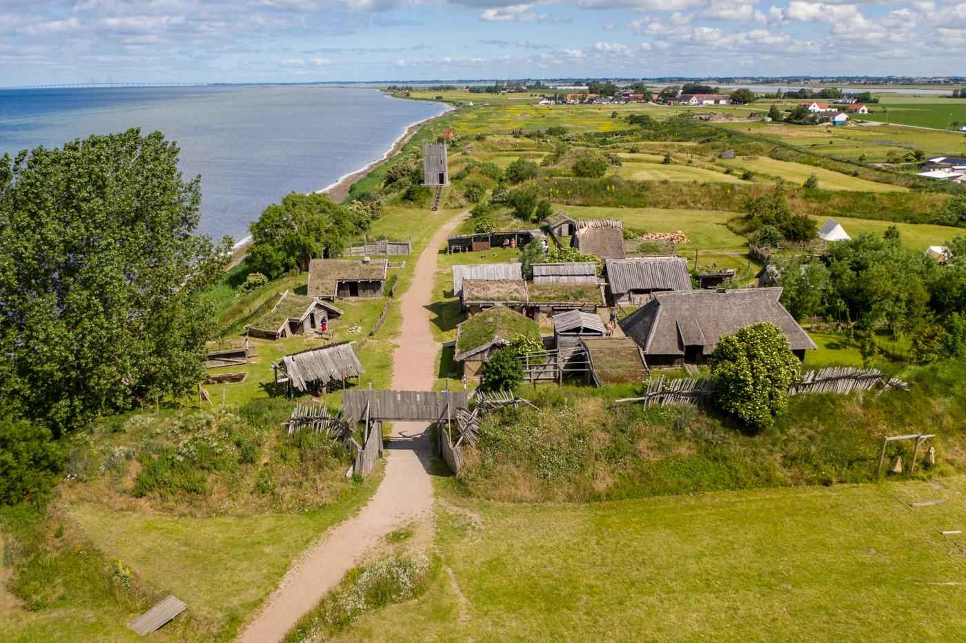 An aerial view of a viking village situated by the sea.