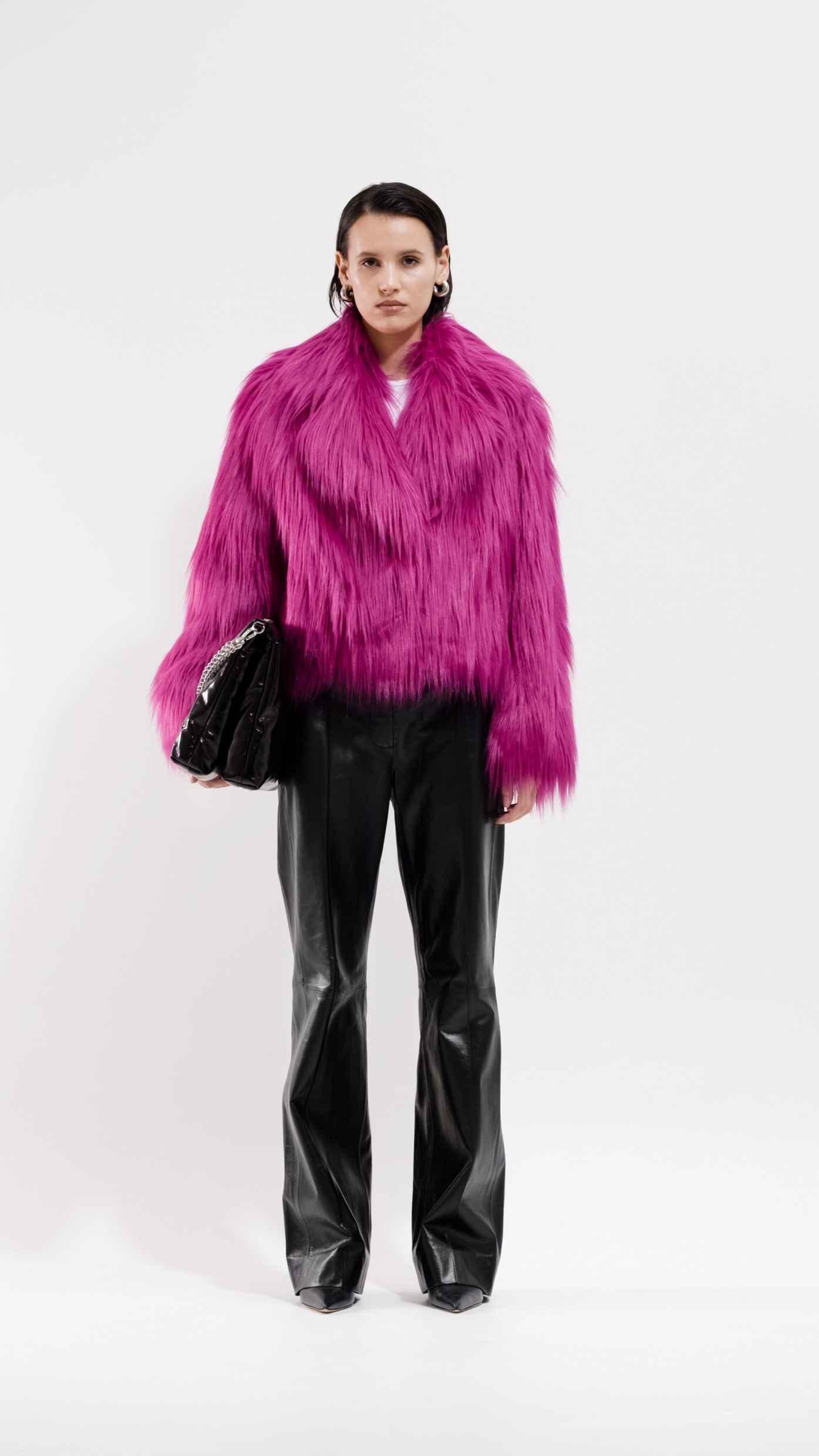 A woman in black vegan leather pants and a pink faux fur jacket.
