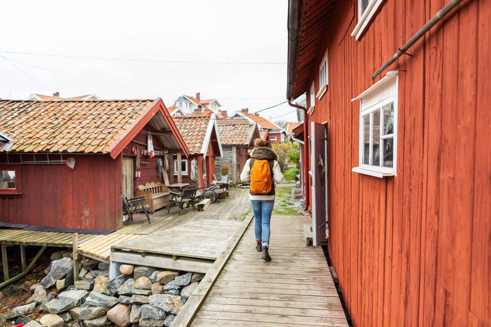 A person with a backpack walks among red wooden houses.