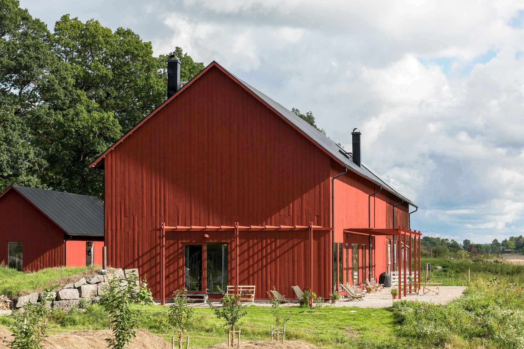 A large red wooden barn during summer.