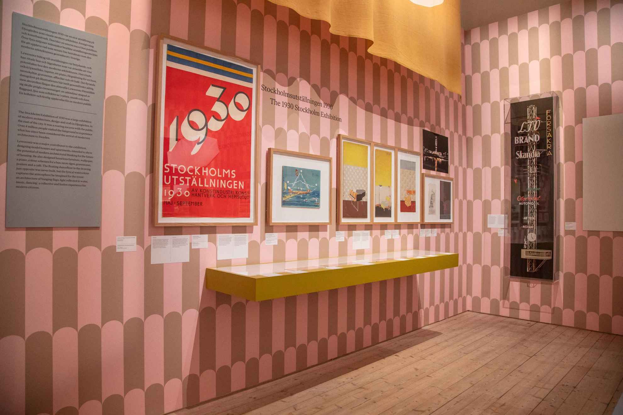 An art exhibitions with paintings on a brown and pink wall.