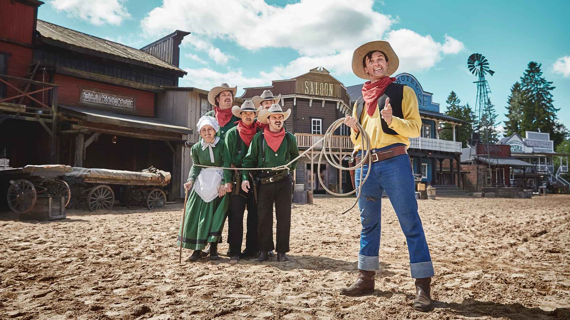 A man dressed as the character Lucky Luke has a lasso around a group of other costumed characters at High Chaparral in Småland.