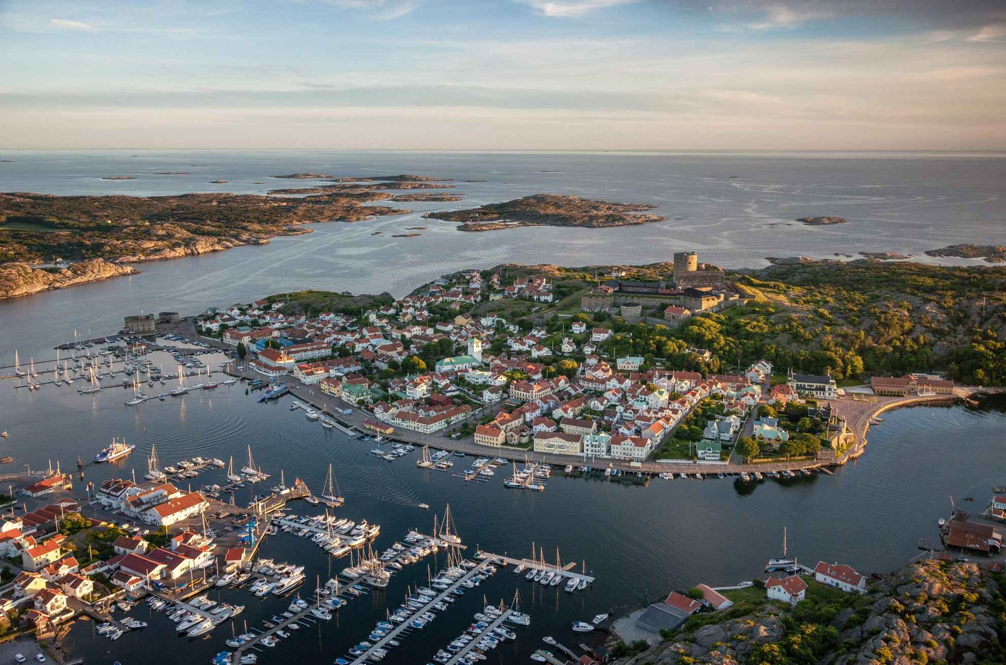 Aerial view of the small town Marstrand with a lot of sailing boats in the front, the fortress on the island in the middle and the archipelago in the background.