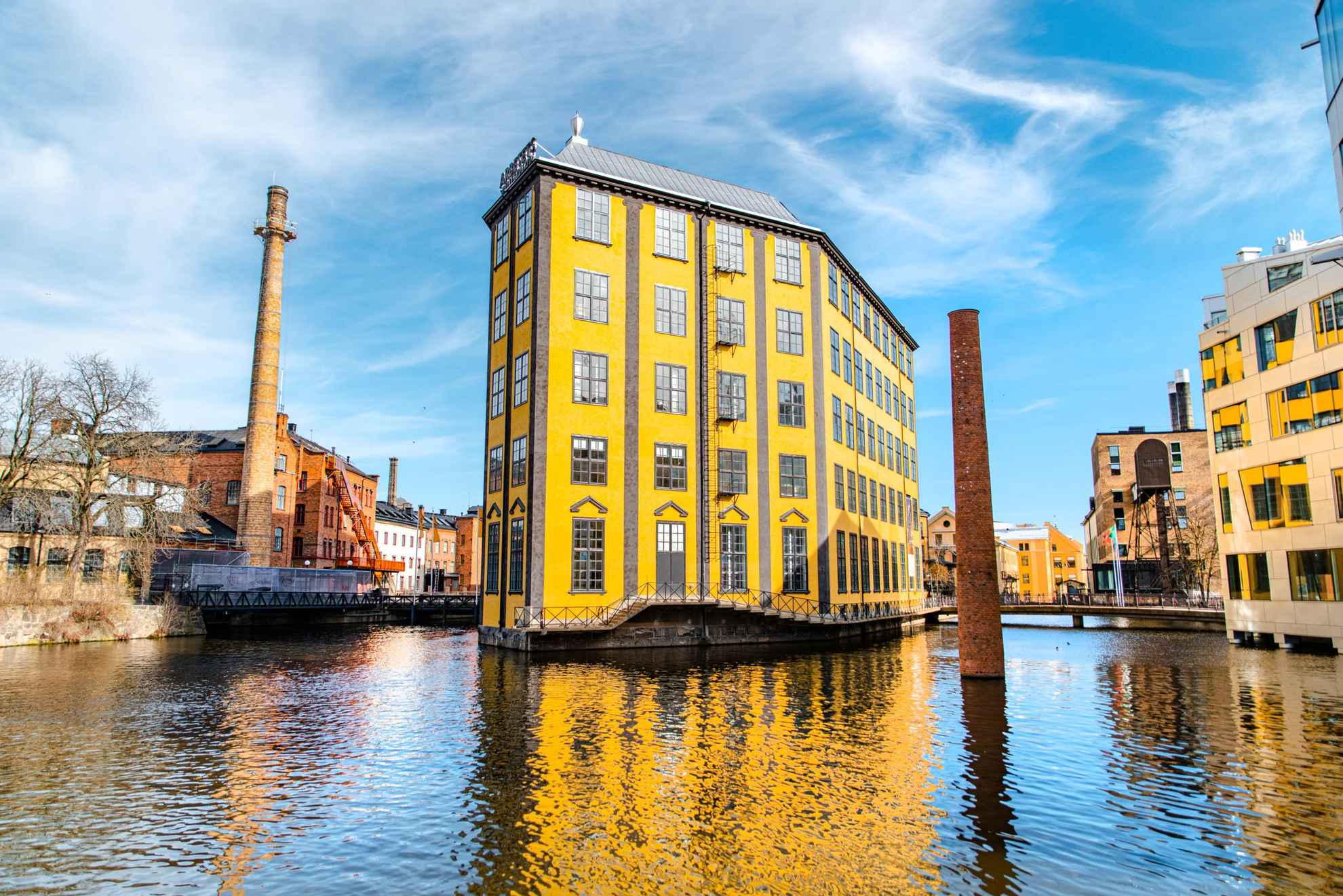 An industrial building with a unique architecture that reminiscent of a flatiron is surrounded by water.