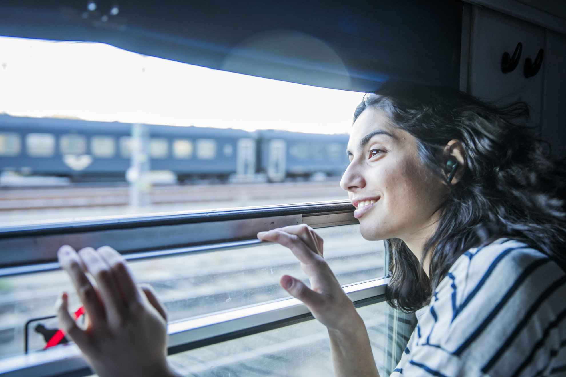 A woman is looking out of the window on a train that are passing another train.