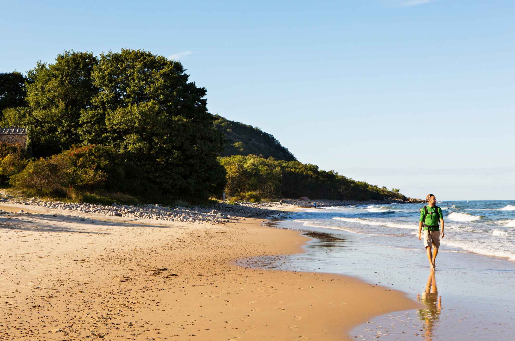 A man walks along the beach on a sunny day.