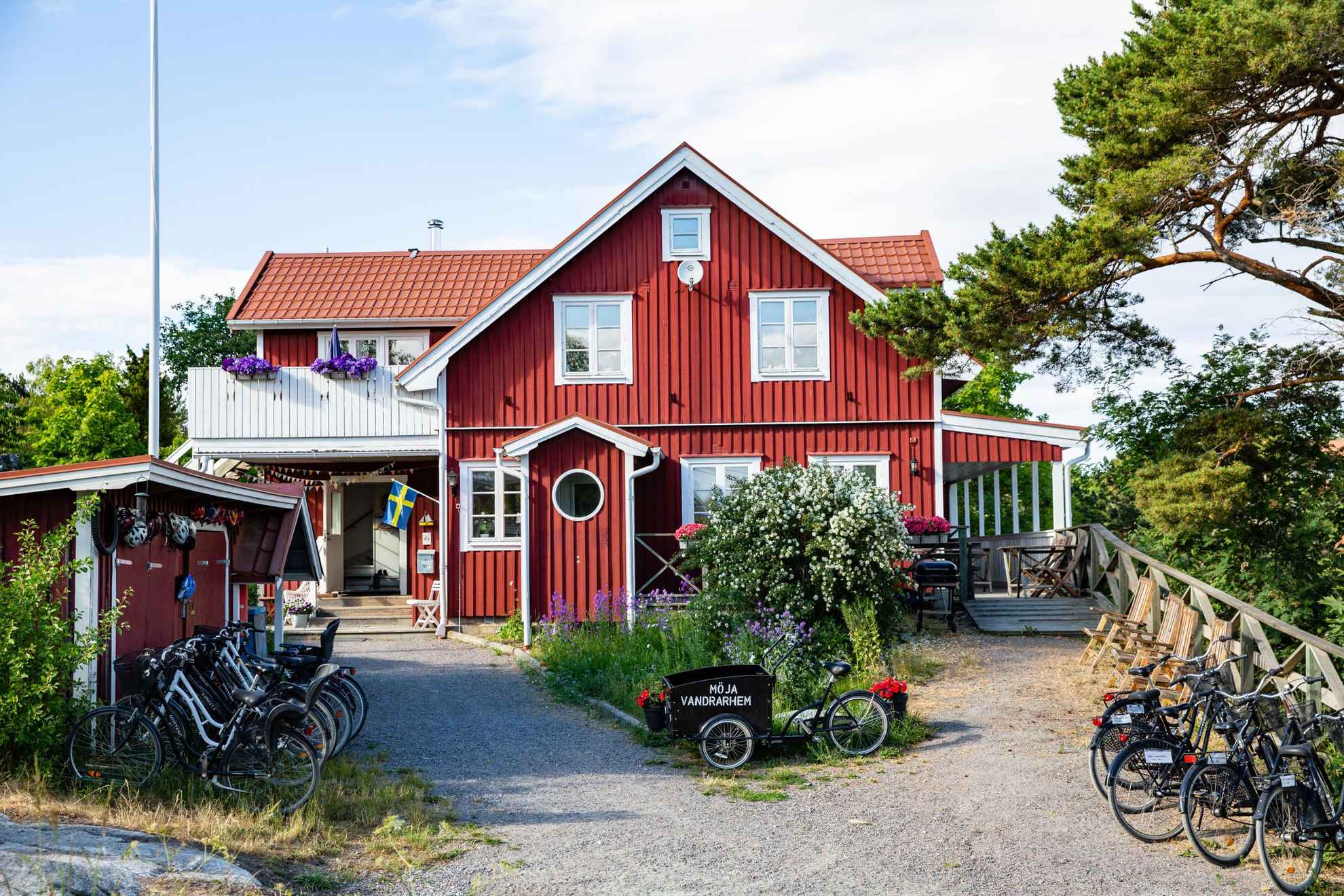 A red wooden house with white trims during summer. Outside the house is several bicycles. On one bike it says "Möja Vandrarhem".