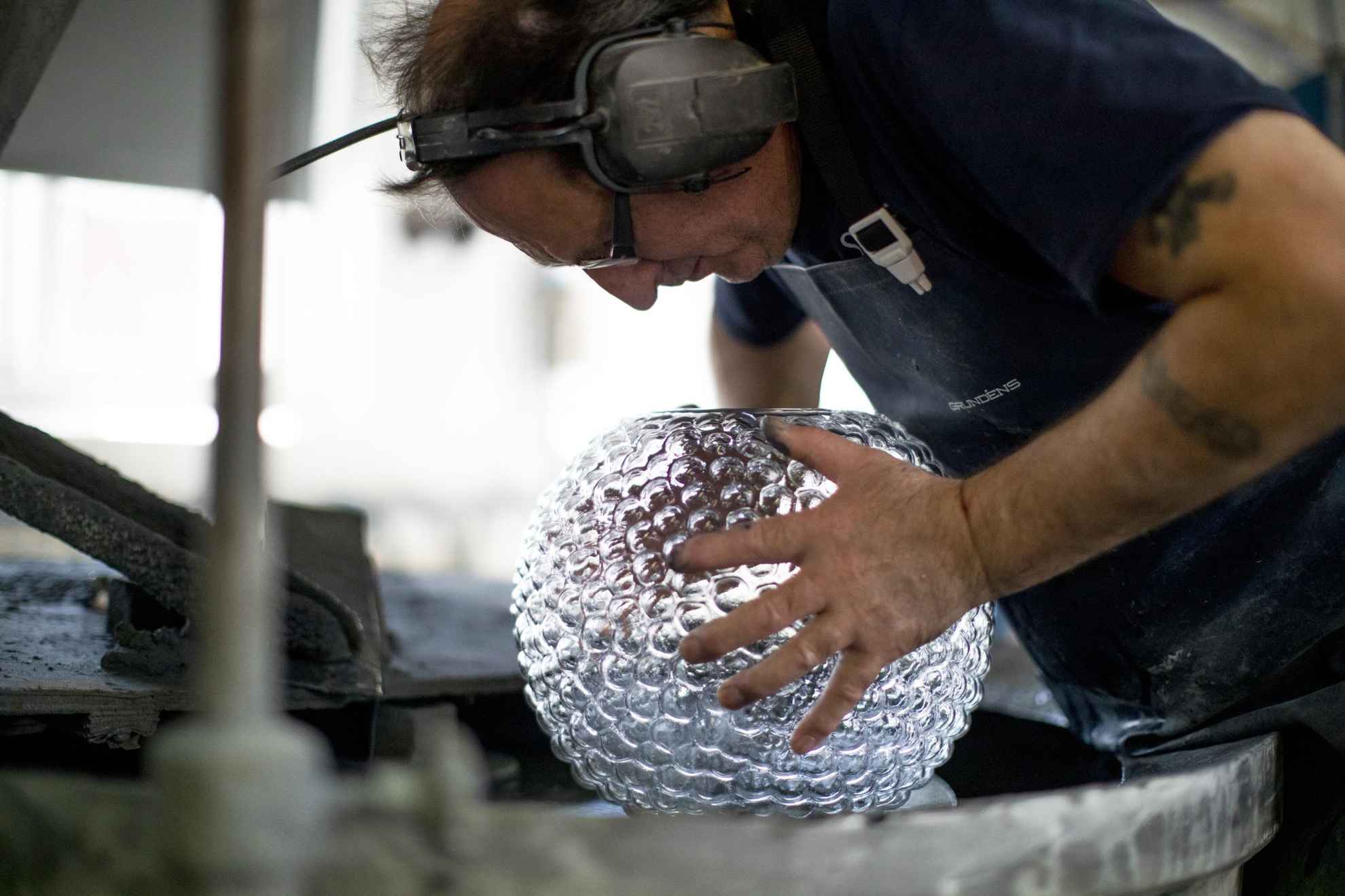 A man is working on a large glass vase Dagg at Skruf Glassworks.