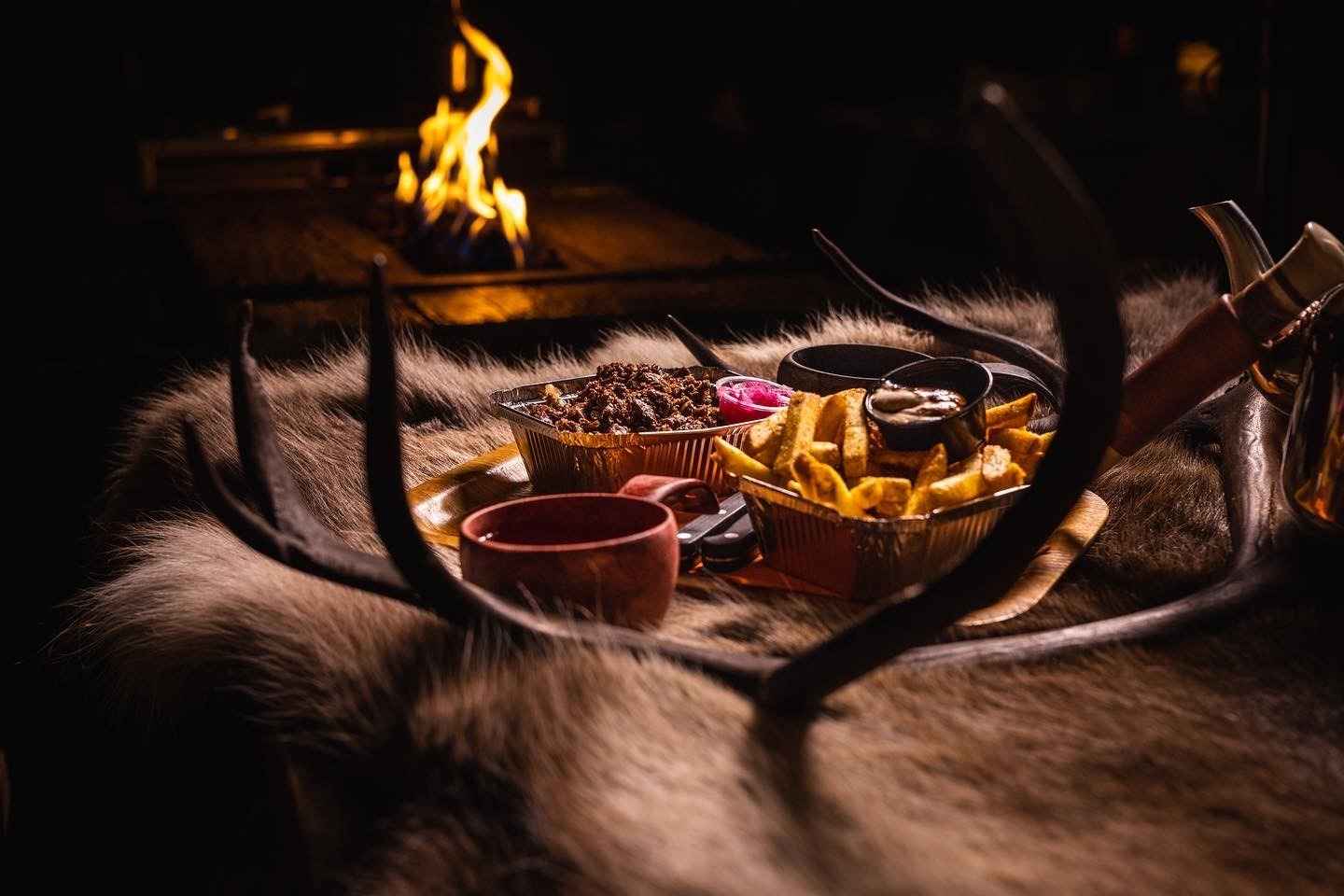 Food served in front of a fireplace in a lavvu.