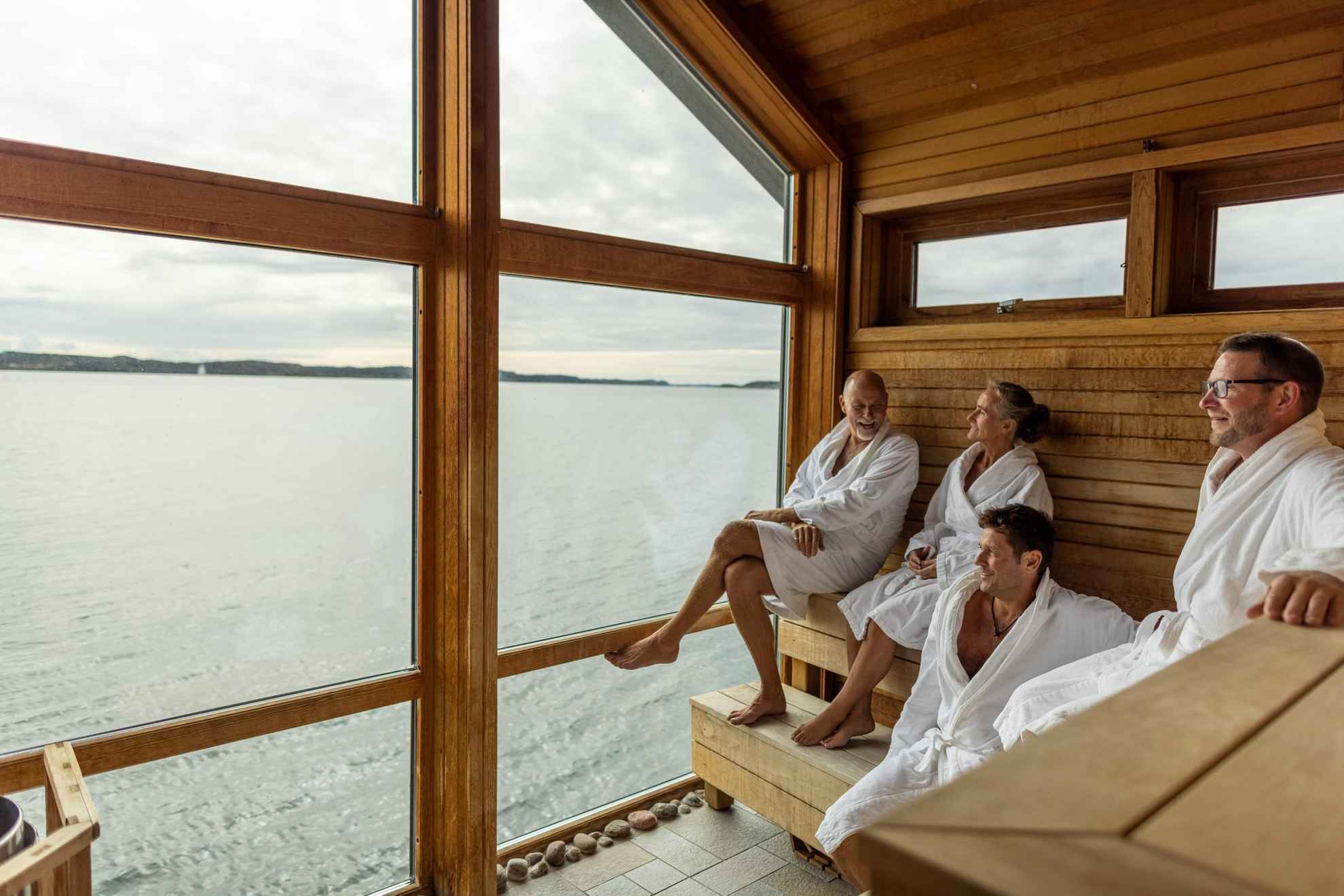 Four people enjoying the sauna and the view of the sea.