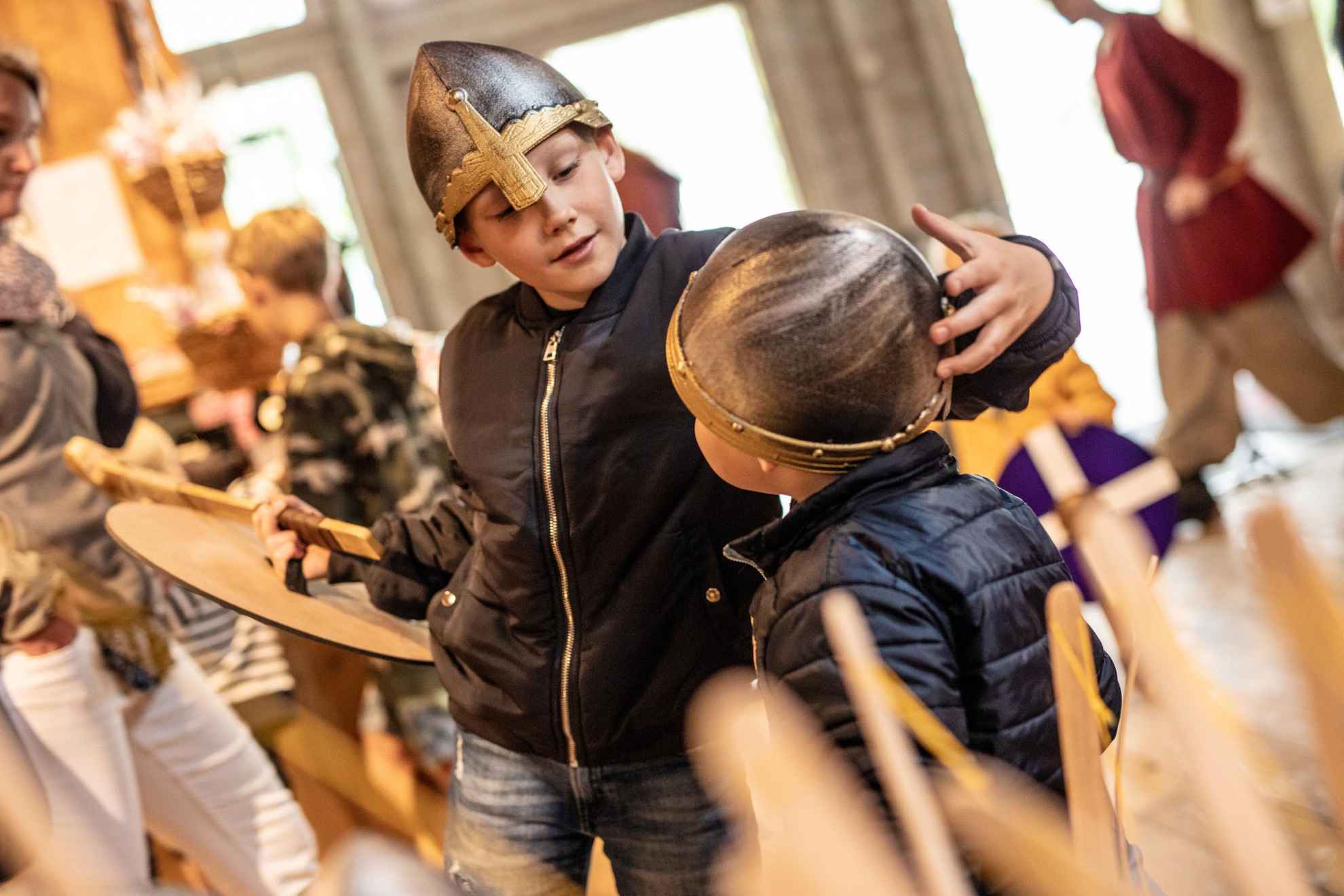 Two children trying on Viking helmets