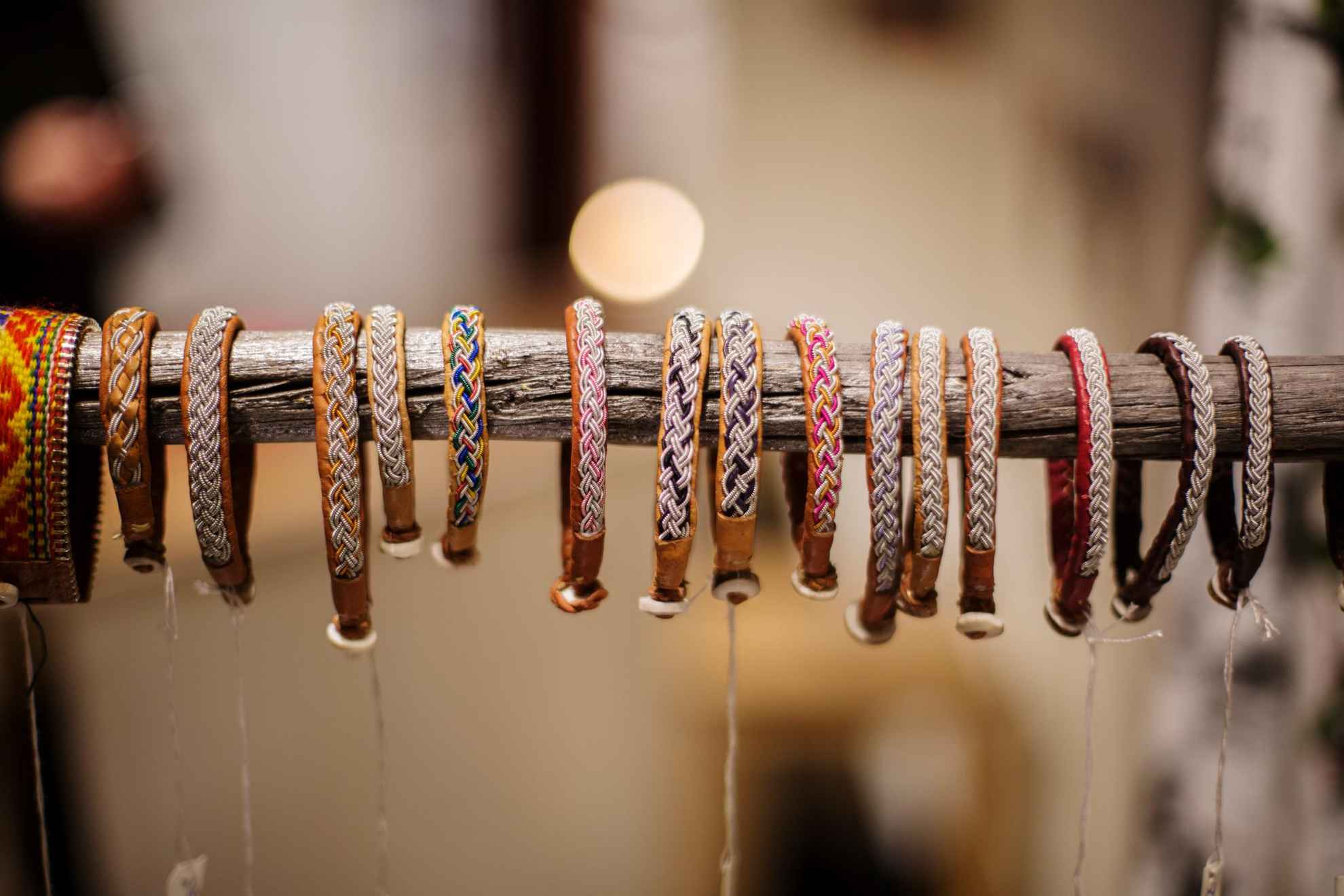 Numerous bracelets made of reindeer leather and tin thread, hanging on a long stick.