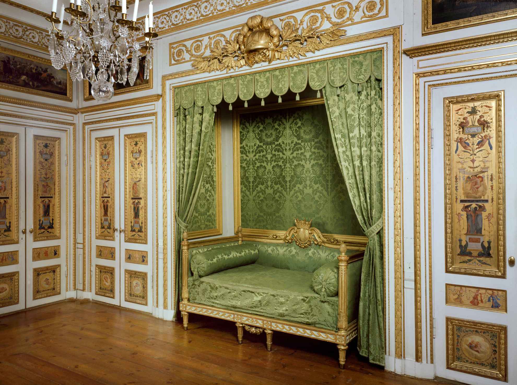 A bed chamber at Tullgarn Palace, decorated with a green couch, golden walls and a chandelier.