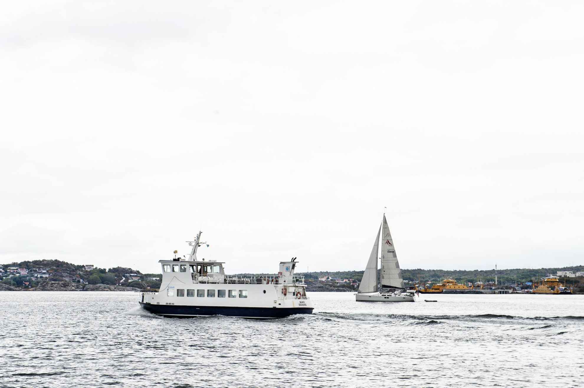 A small ferry and sailboat in the sea by an island outside Gothenburg.