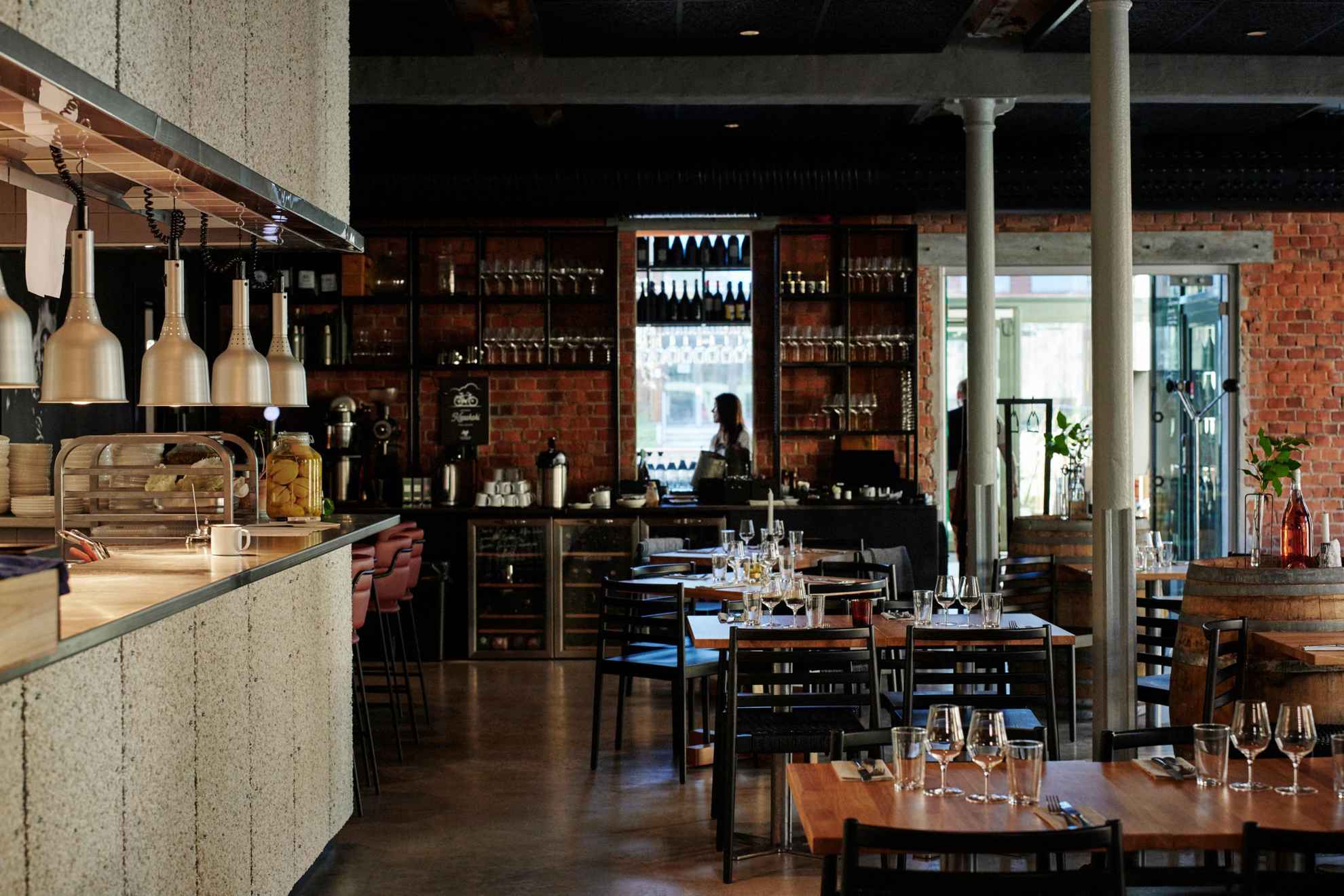 Interior of a wine restaurant with several tables and a bar on the left.