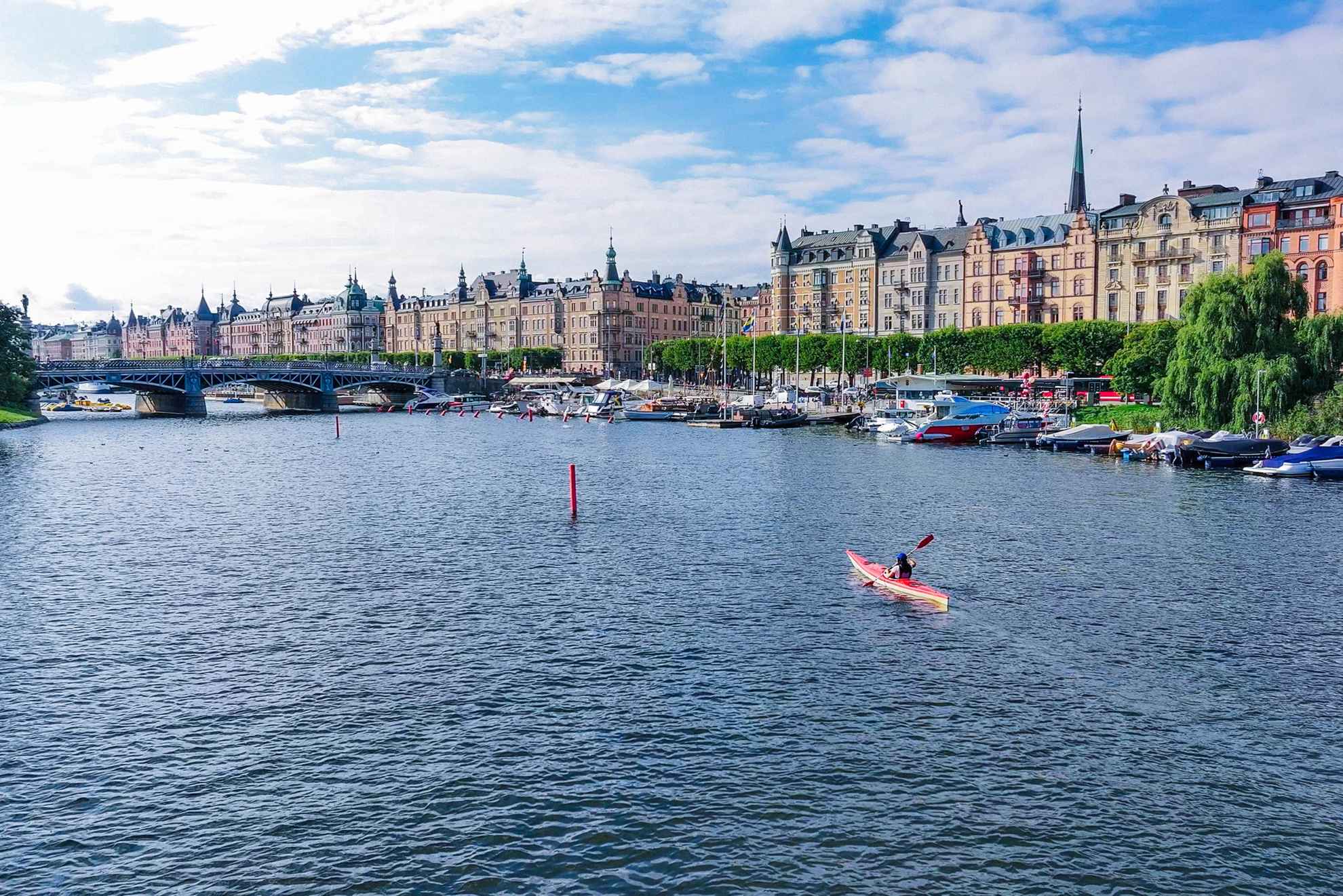 A woman is kayaking in the centre of Stockholm on a sunny summer day.