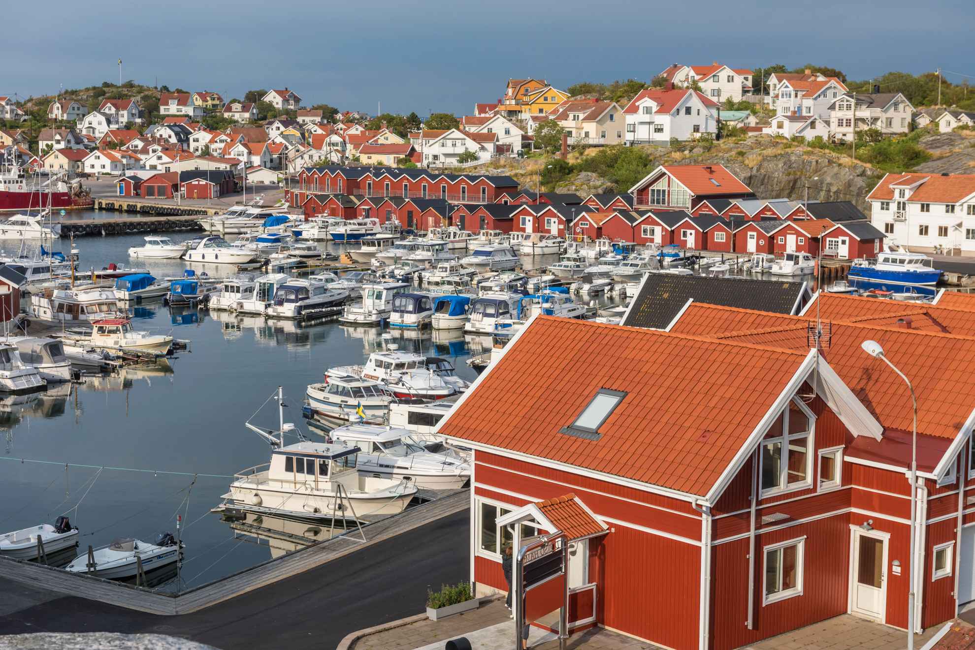 A harbor with boats, red fishing huts and white houses.