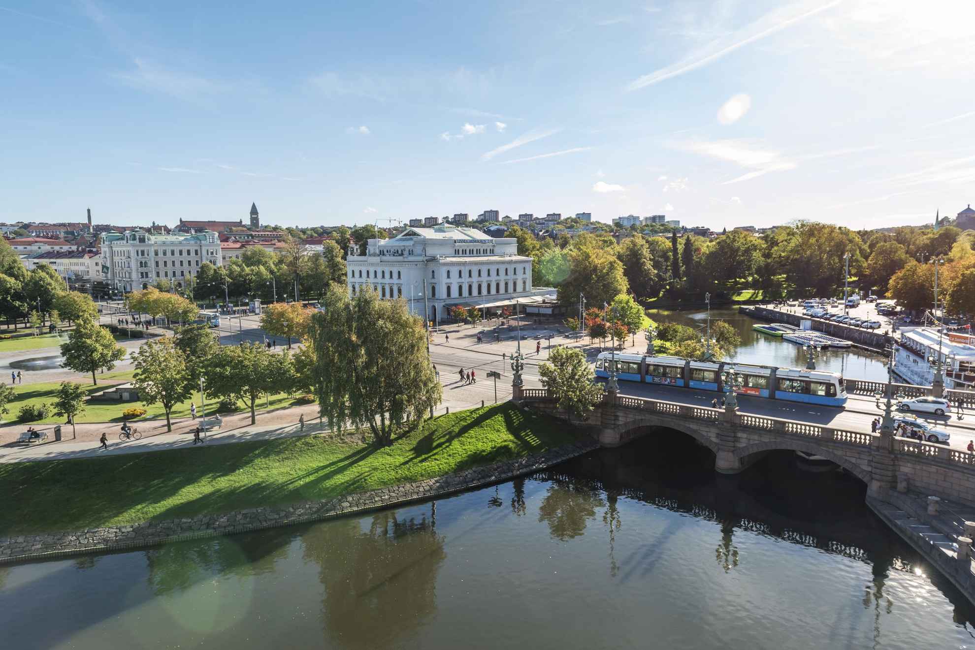 Aerial view of Kungsportsavenyn and the theatre Stora Teatern. A tram crosses the bridge Kungsportsbron. Green trees surround the streets.