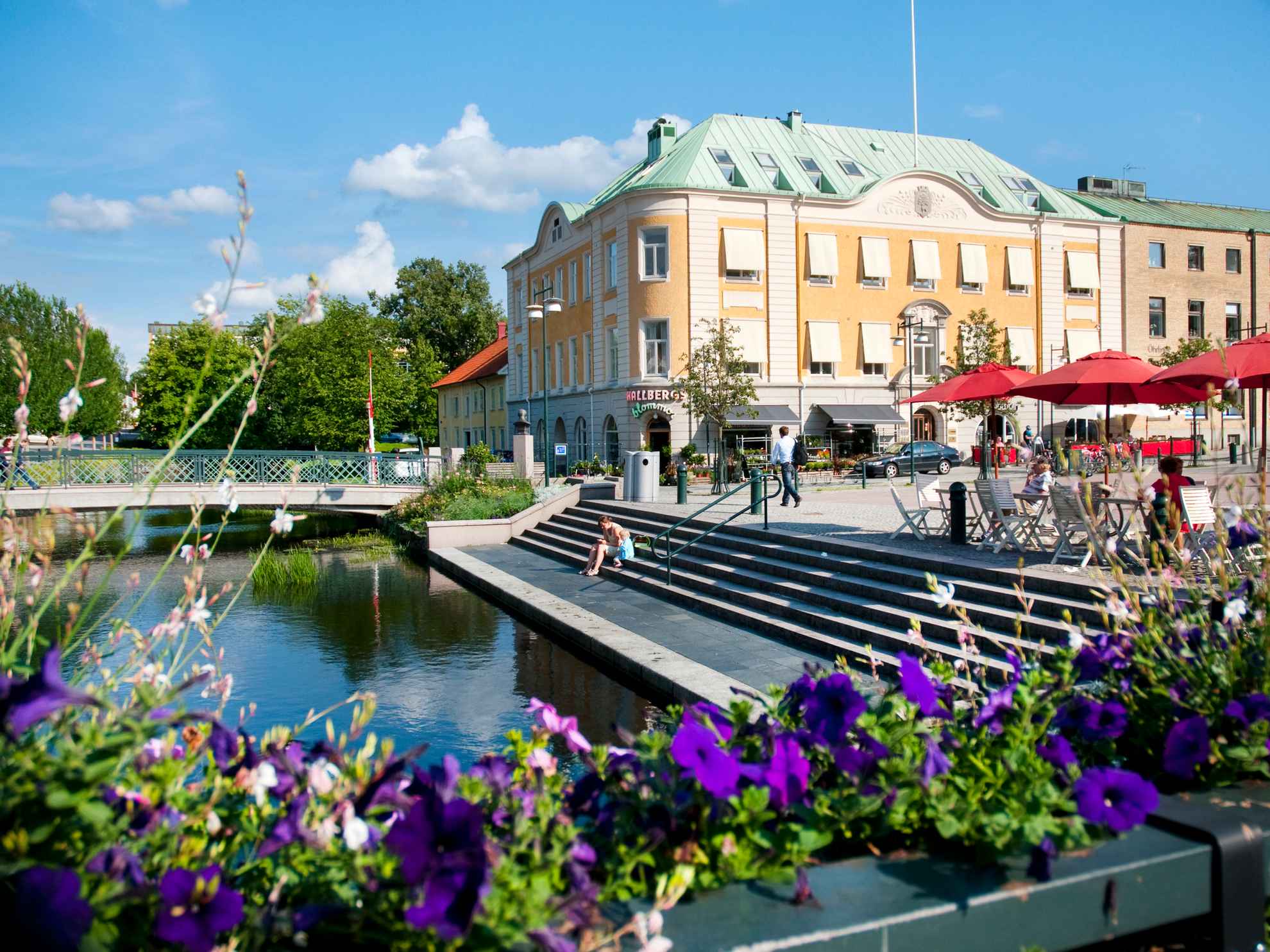 Sunny day in Alingsås. City centre with stairs and a bridge over Lillån. Purple flowers in the foreground.