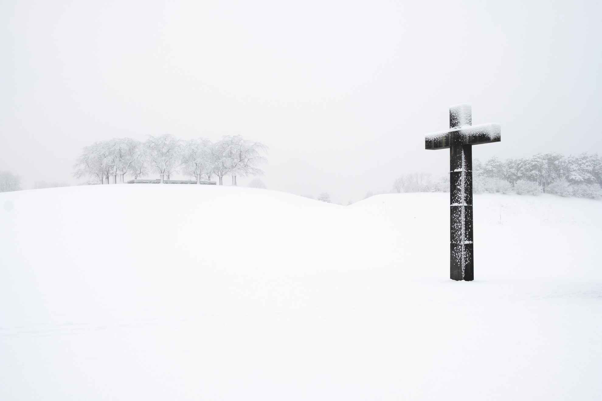 A snow-covered landscape with a large cross in the foreground.