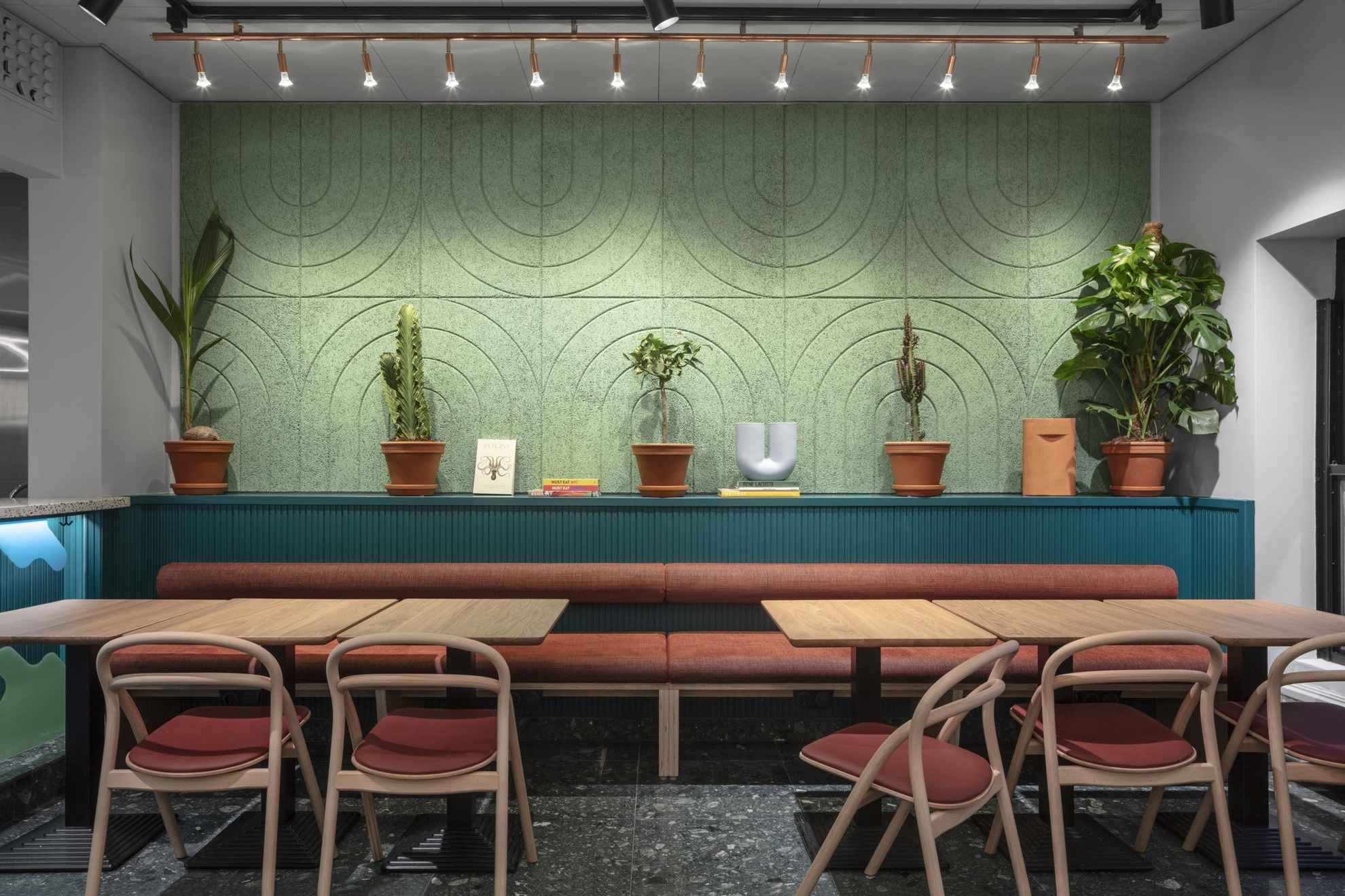 A seating area. A few plants are decorating the green and blue wall behind the table.