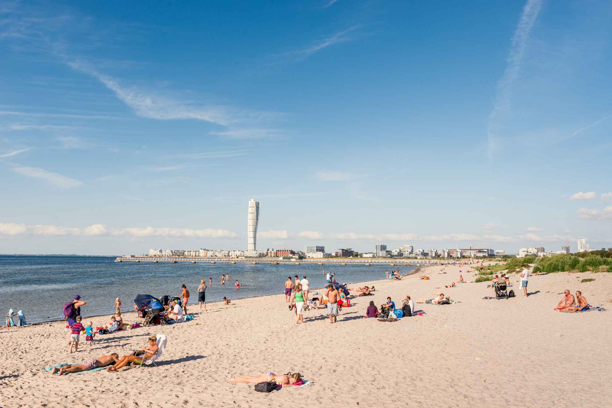 People enjoying themself at a beach in Malmö. In the horizon you can glimt the building "Turning Torso".