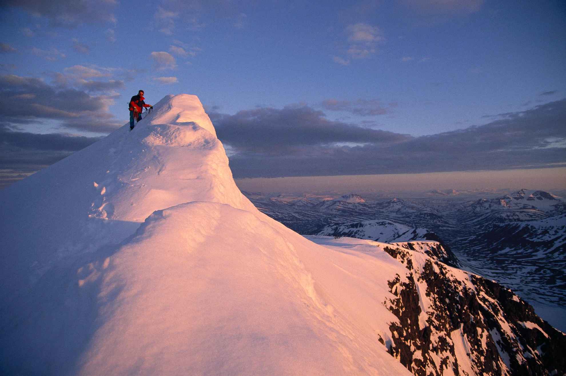 A person stands on top of a snowy mountain.