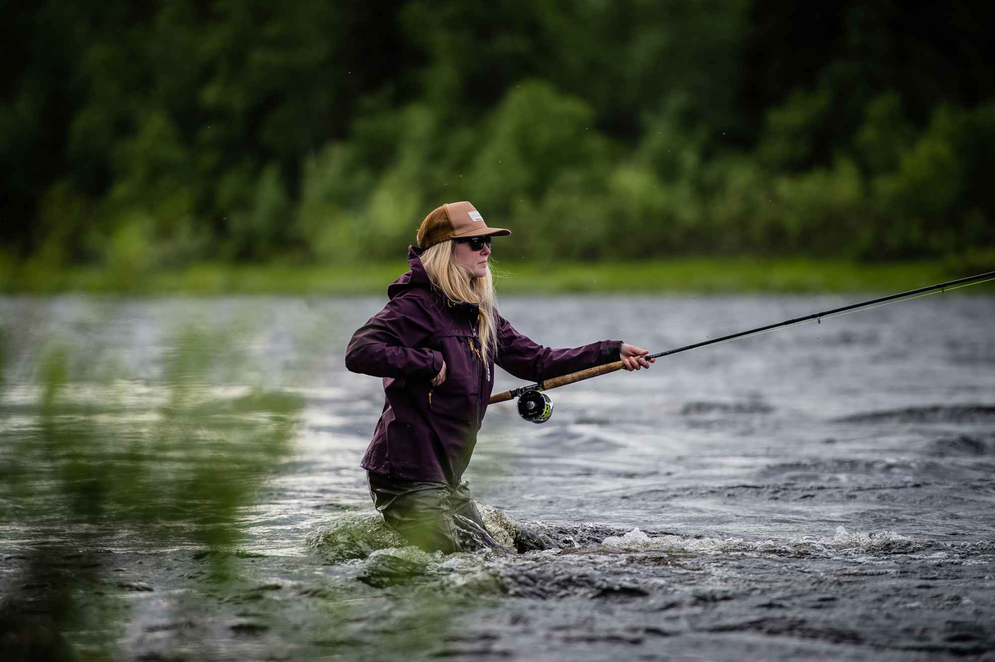 A girl is fly fishing in a river.