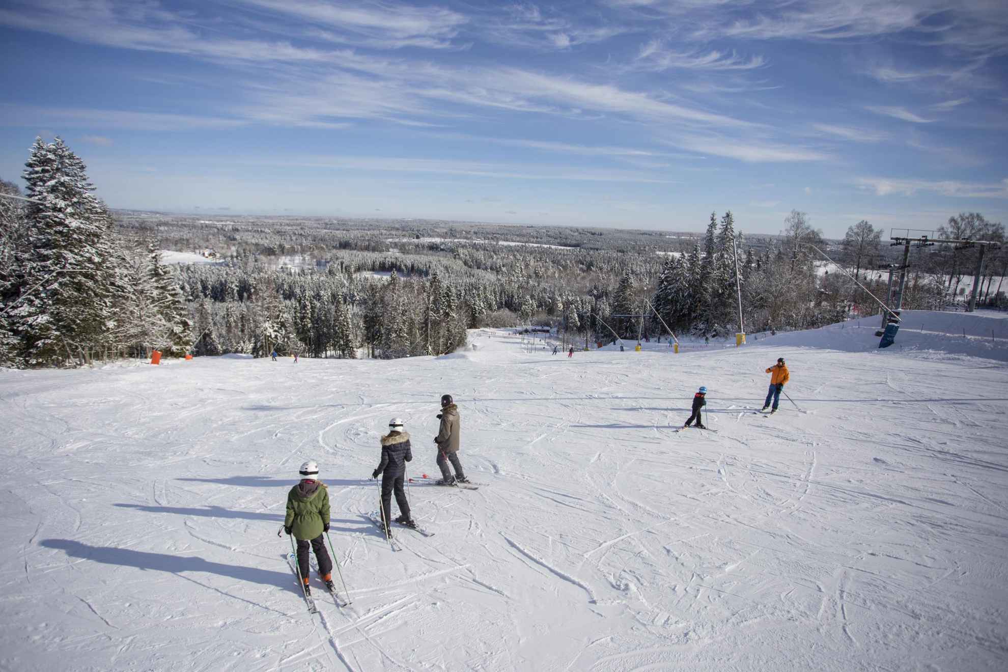 People skiing down a slope with a view of a snow-covered landscape.