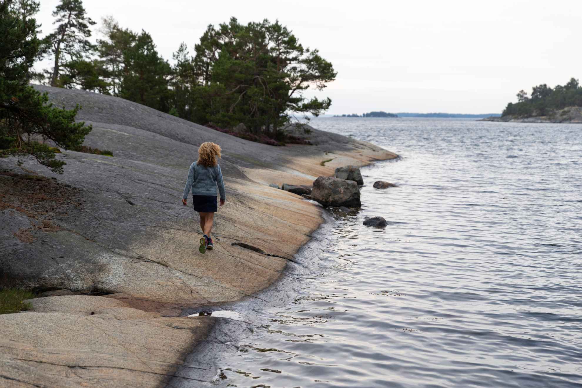 A woman walks on cliffs along the waterfront in the Stockholm archipelago.
