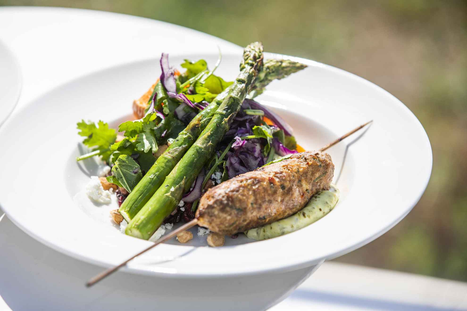 A plate with salad, aspargus and lamb skewers sourced in Sweden.