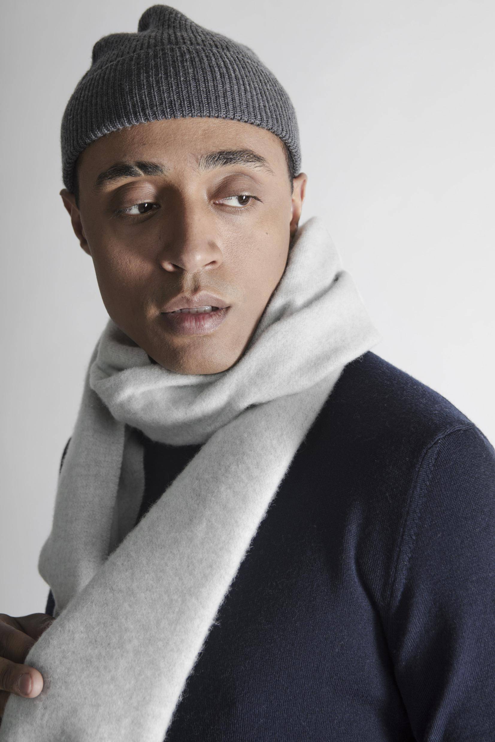 A portrait of man with a beanie and scarf.