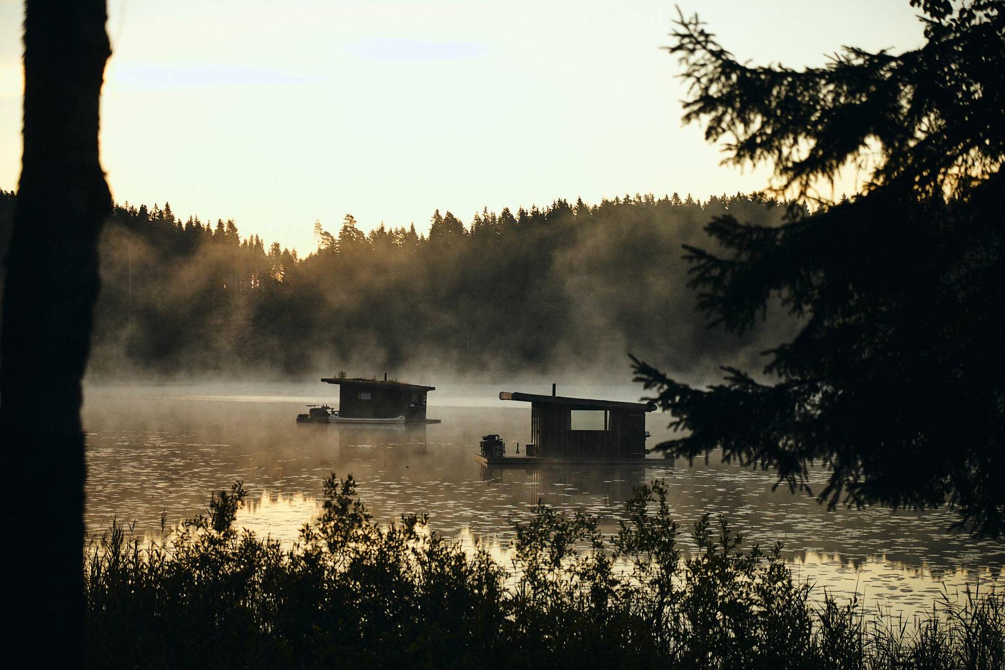 Two wooden houseboats on a foggy lake.