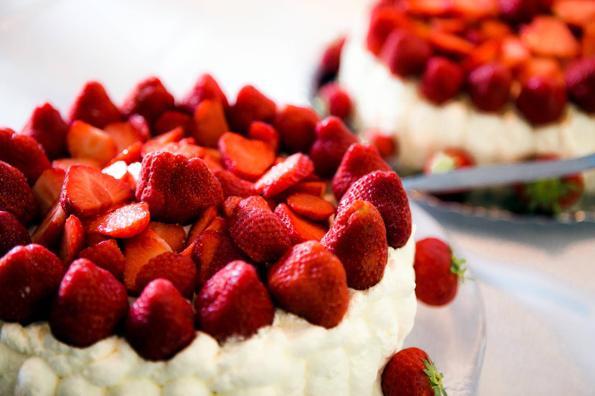 Two cakes with whipped cream and strawberries.
