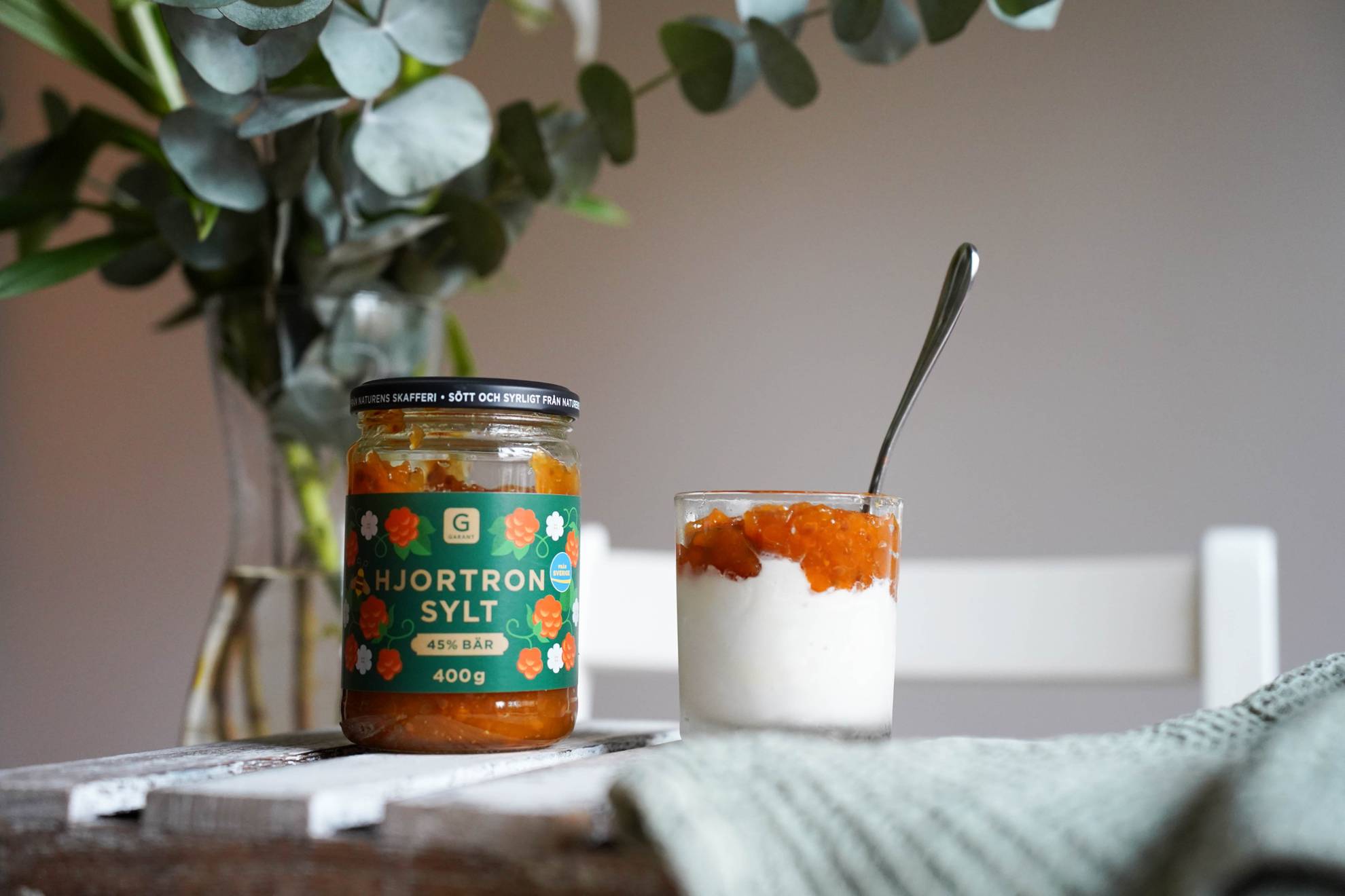 A jar of Cloudberry jam and a glass with ice cream and cloudberry jam on the side.