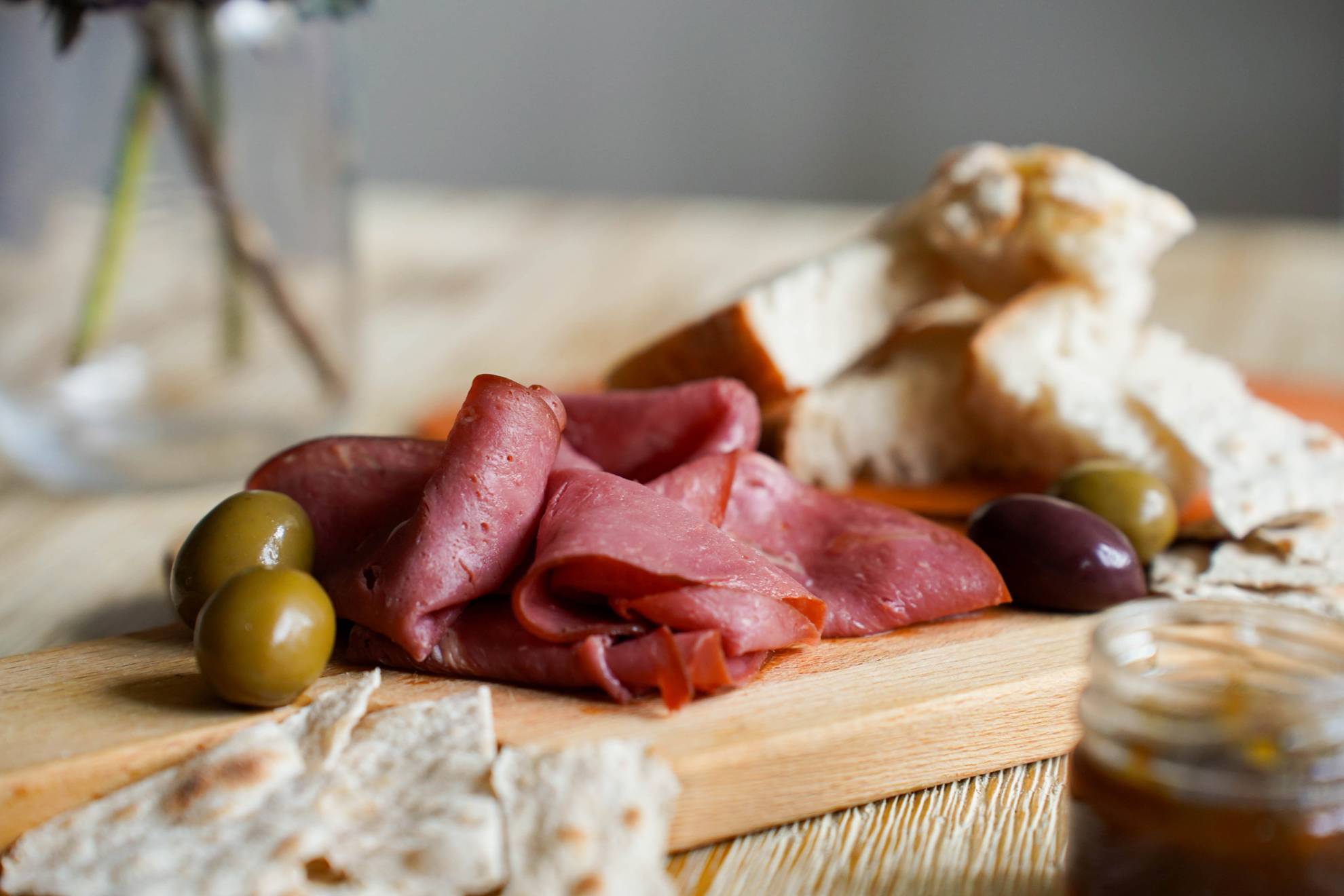 A charcuterie board with olives, bread and smoked reindeer meat.