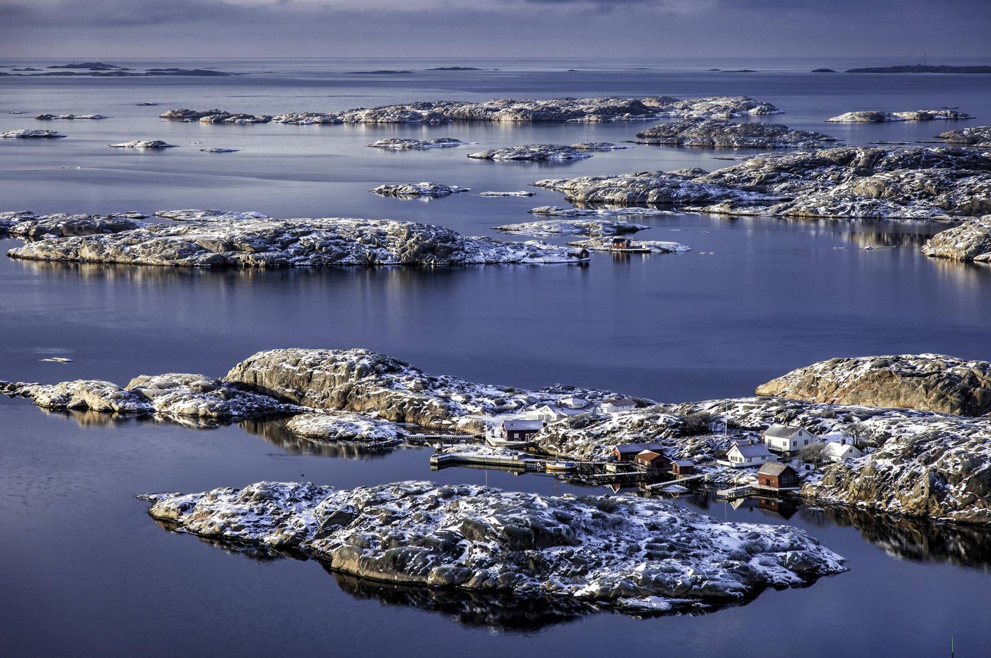 Scenic view of the west coast archipelago at winter. The houses and islets are covered in frost and a little snow.