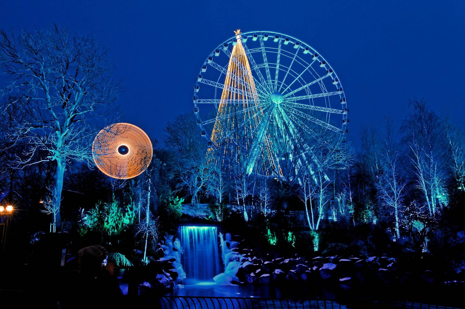 A ferris wheel and a waterfall, nighttime at Liseberg amusement park.