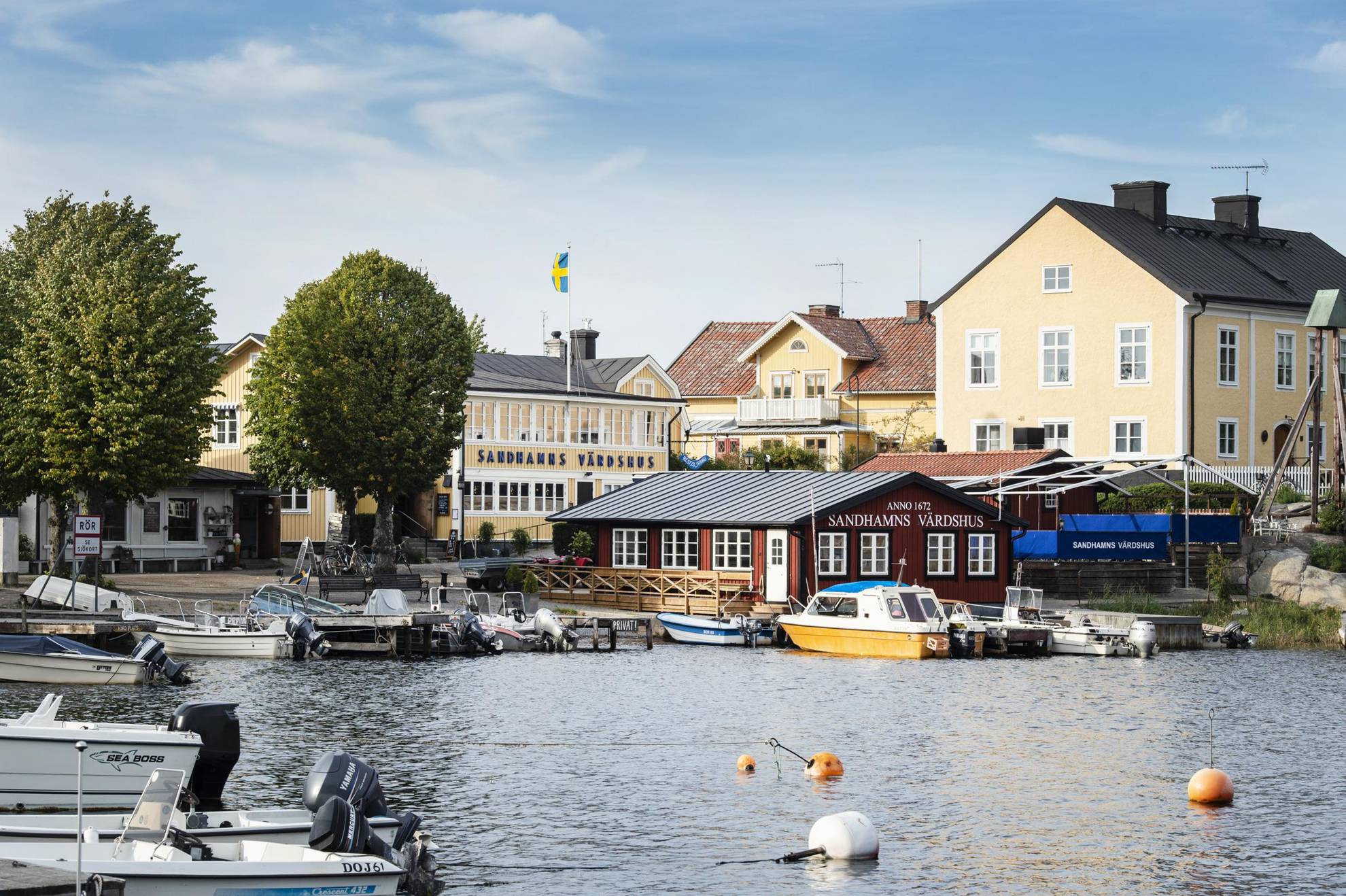 Houses in yellow and red, located by a harbour with many small boats in Sandhamn.