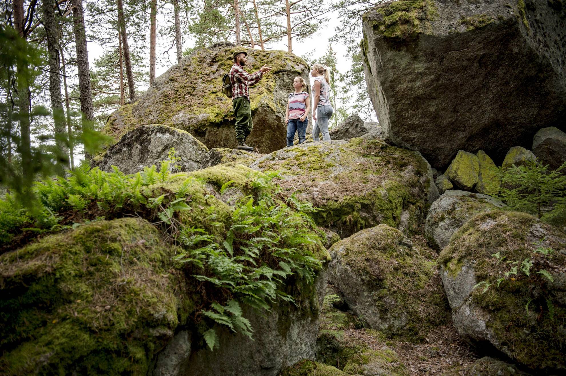 Two women are listening to a guide while standing in a forest.
