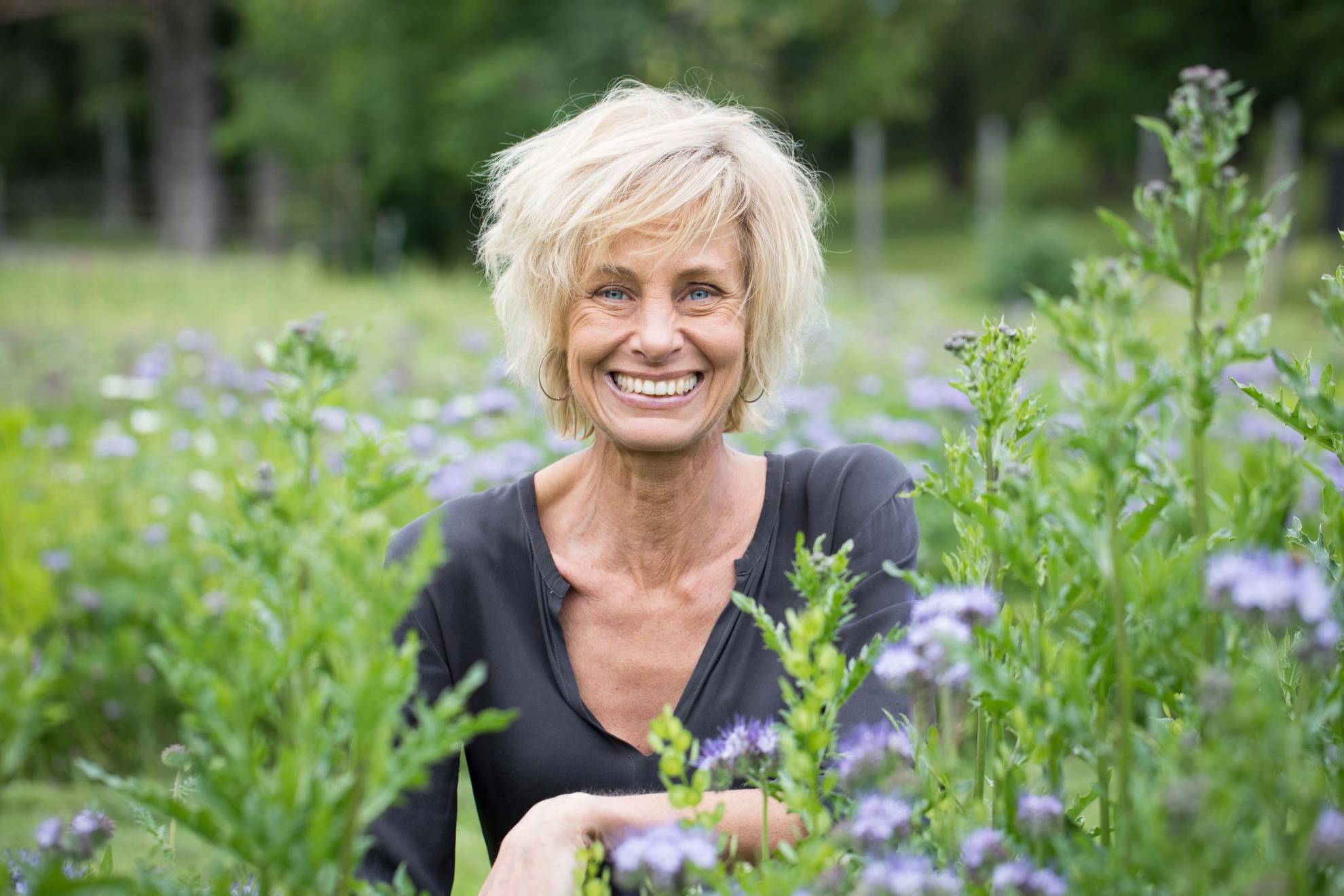 A portrait of Lisen Sundgren in nature surrounded by greenery. She is smiling into the camera.